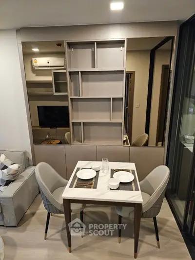 Modern dining area with elegant table and chairs, adjacent to cozy living room and stylish shelving.