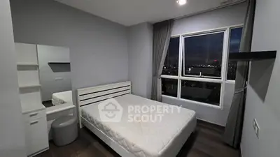 Modern bedroom with city view, featuring sleek furniture and large window for natural light.