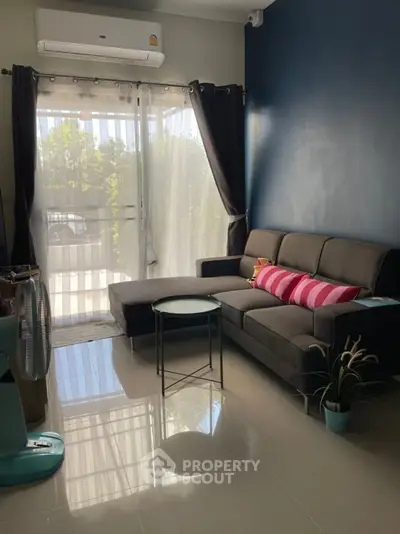 Cozy living room with modern sofa and natural light through large windows.