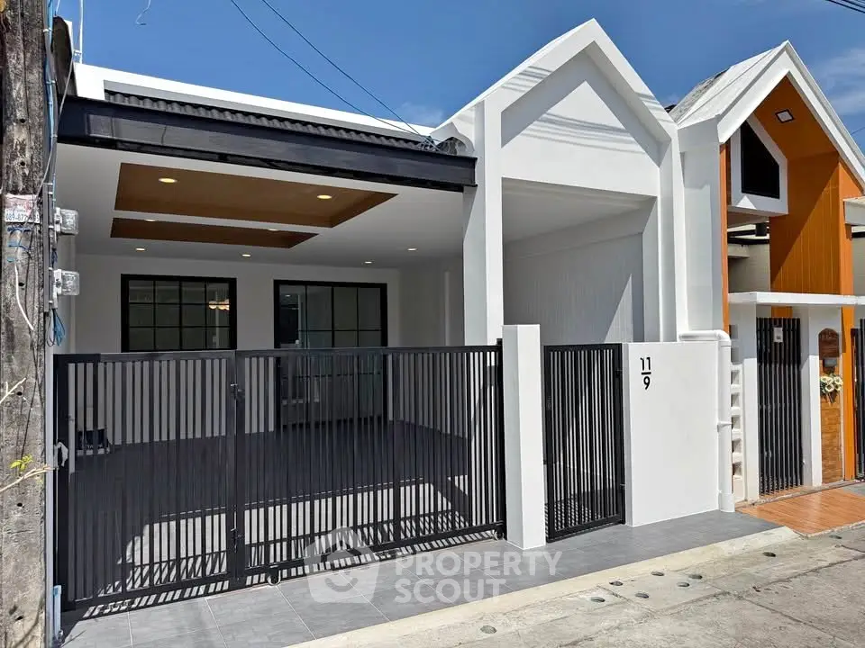 Modern single-story house with gated entrance and sleek design in a suburban neighborhood.