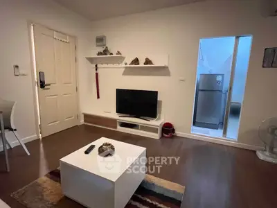 Cozy living room with modern decor and TV setup, adjacent to a compact kitchen area.