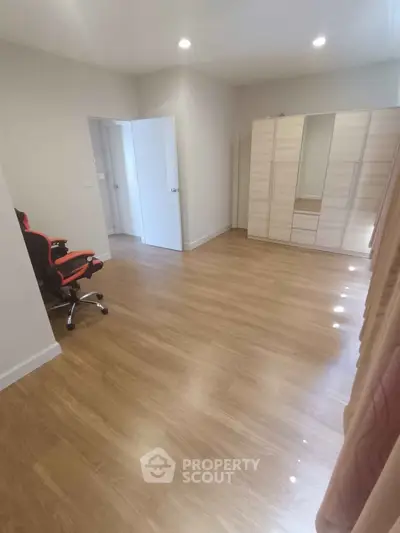 Spacious bedroom with wooden flooring and modern wardrobe