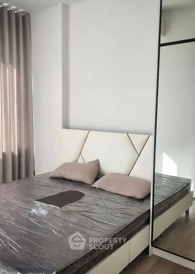 Modern bedroom with stylish bed and mirrored wardrobe in a bright apartment.