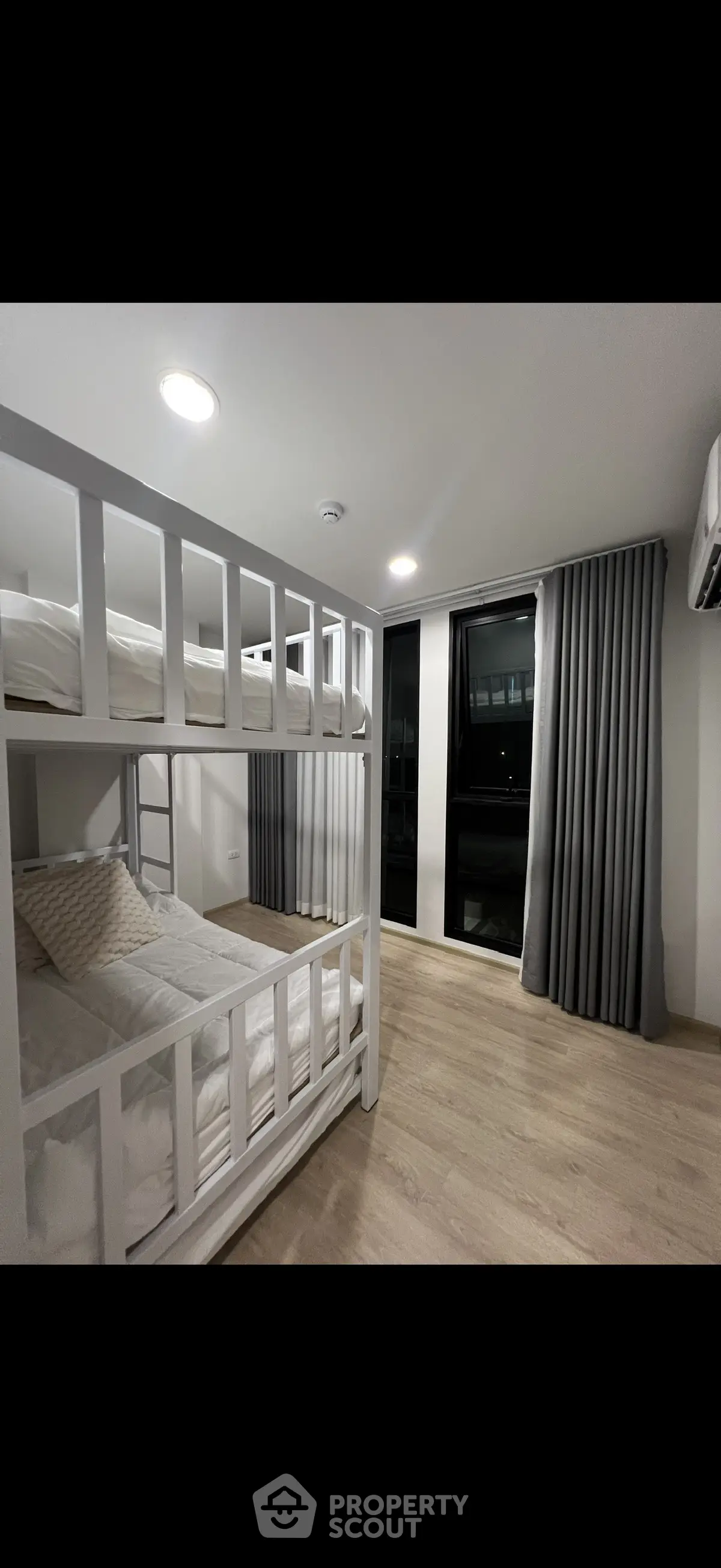 Modern bedroom with bunk beds and large window, featuring sleek design and ample natural light.