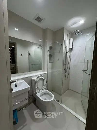 Modern bathroom with glass shower and sleek fixtures in contemporary apartment.