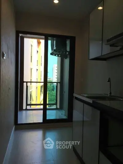 Modern kitchen with sleek cabinetry and balcony access in urban apartment.