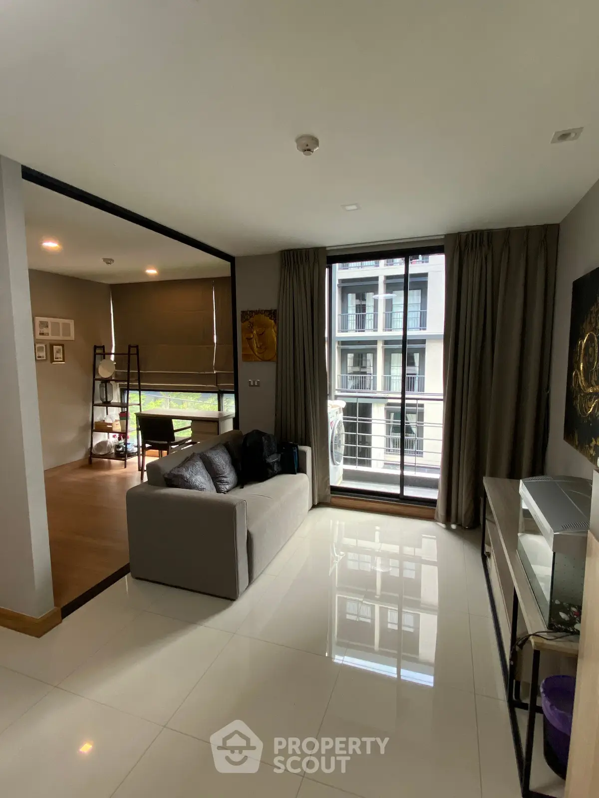 Modern living room with sleek design and large window offering natural light and urban view.