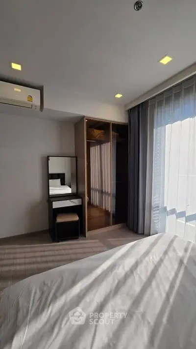 Modern bedroom with large window, built-in wardrobe, and air conditioning unit.