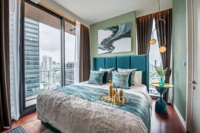 Luxurious bedroom with stunning city view and modern decor in high-rise apartment.