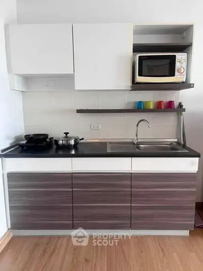 Modern compact kitchen with sleek cabinetry and built-in microwave