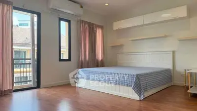 Spacious bedroom with large windows and modern furnishings in a bright, airy apartment.