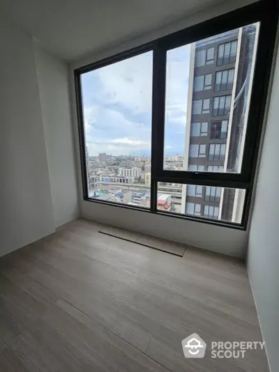 Spacious room with large windows offering stunning city views in modern high-rise building.