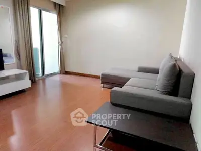 Spacious living room with modern gray sofa and sliding glass doors leading to balcony.
