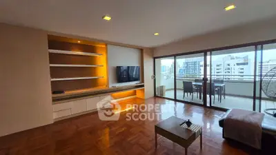 Spacious living room with modern entertainment unit and large balcony overlooking cityscape.