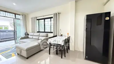Modern living room with sleek sofa and dining area, featuring large windows and a stylish refrigerator.