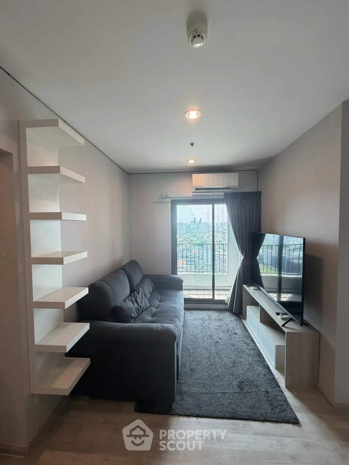Modern living room with city view, featuring a sleek sofa and entertainment unit, perfect for urban living.