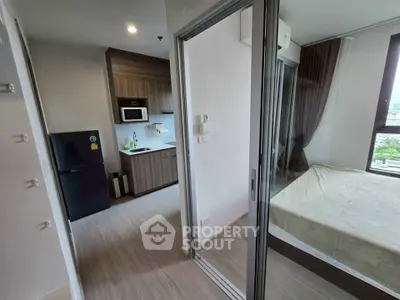 Modern apartment interior with compact kitchen and cozy bedroom, featuring sleek design and natural light.