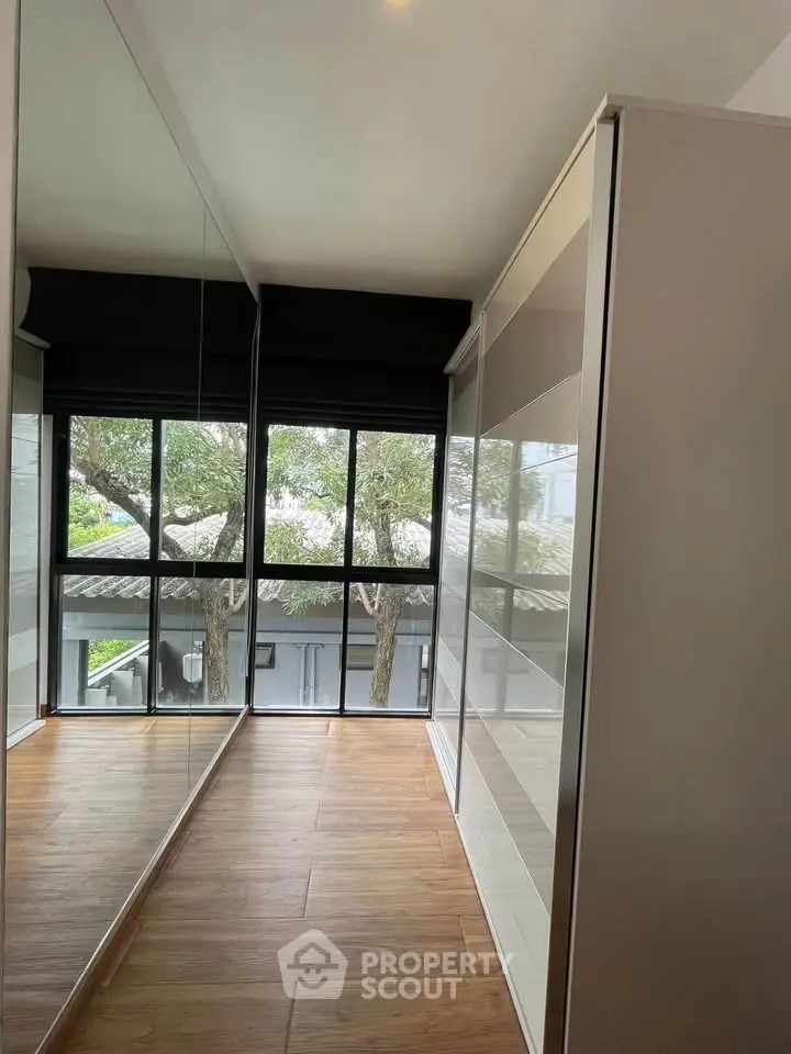 Spacious walk-in closet with large windows and wooden flooring