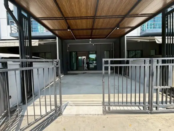Modern townhouse entrance with sleek metal gate and wooden ceiling design.