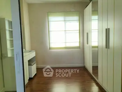 Spacious bedroom with large wardrobe and wooden flooring, perfect for modern living.