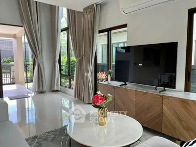 Spacious living room with modern decor and large windows offering garden views.