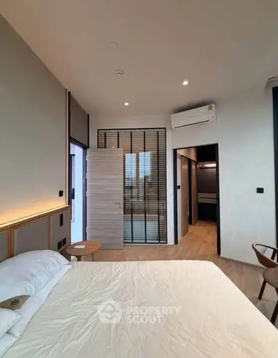Modern bedroom with sleek design, featuring a comfortable bed, stylish lighting, and wooden flooring.