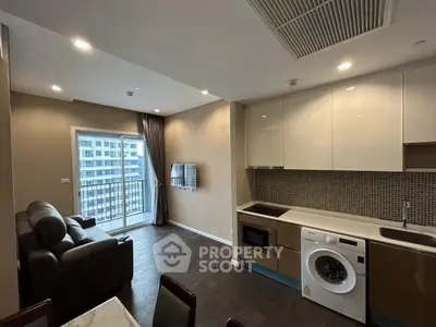 Modern open-layout living room with kitchen, featuring a washing machine and balcony view.