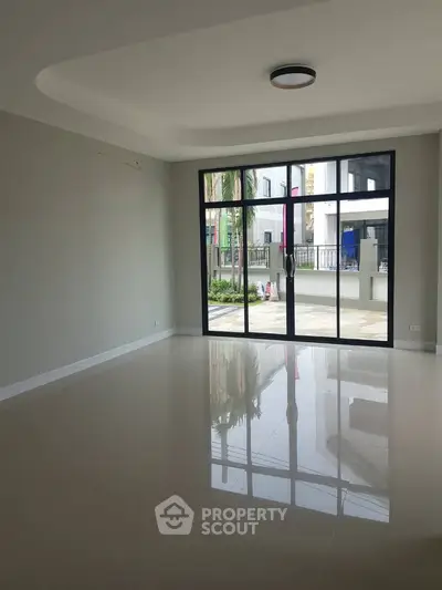 Spacious modern living room with large windows and glossy tiled floor, offering a bright and airy ambiance.