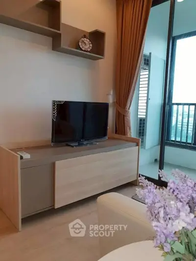 Modern living room with TV, wooden cabinet, and balcony view in a stylish apartment.