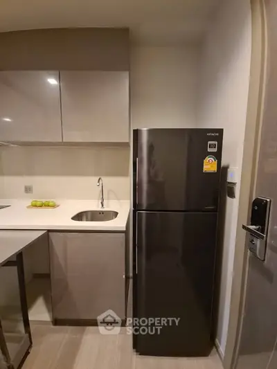 Modern kitchen with sleek cabinetry and stainless steel fridge in a compact layout.
