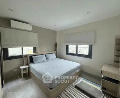 Modern bedroom with stylish decor and natural light, featuring a comfortable bed and sleek furnishings.