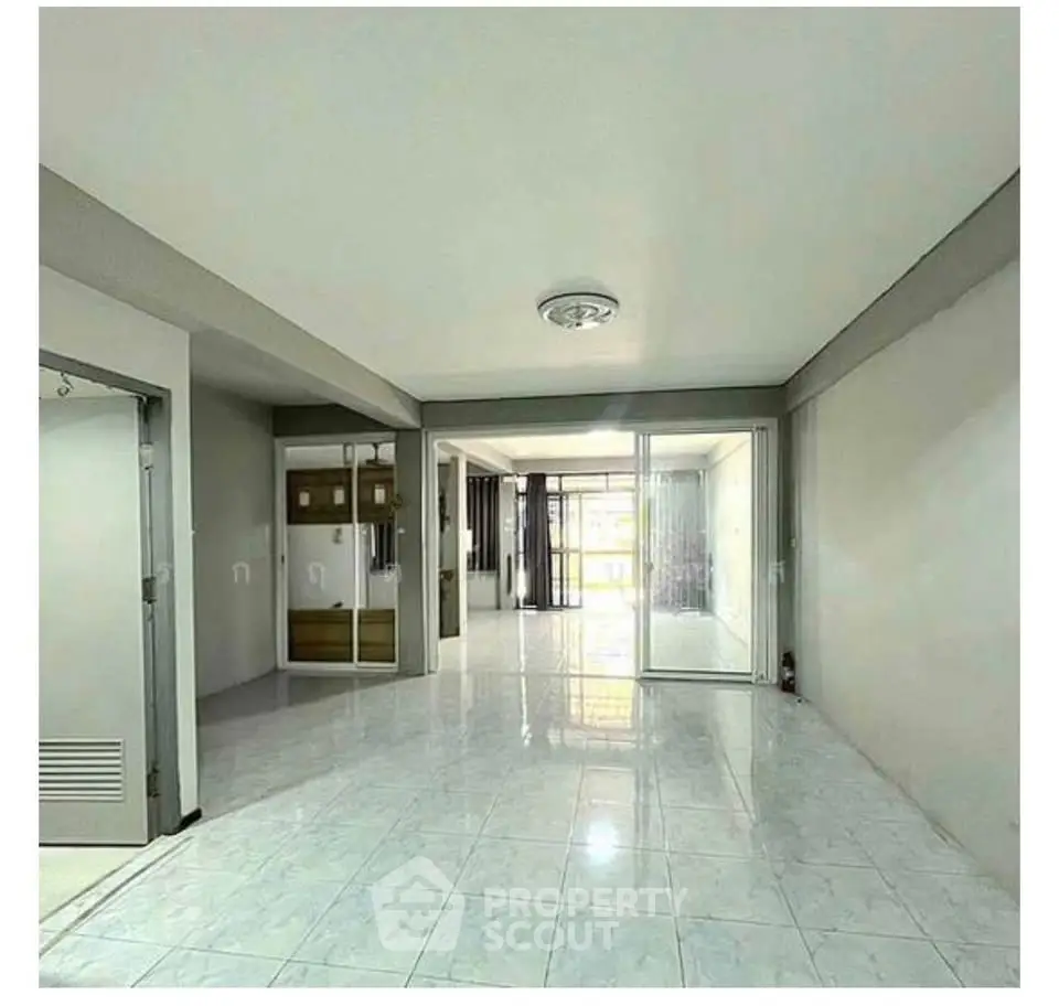 Spacious open-plan living area with large windows and modern tile flooring.