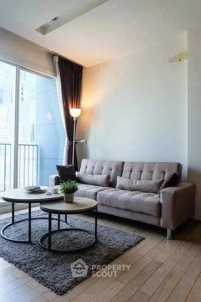 Modern living room with stylish sofa and coffee table, featuring large windows and elegant curtains.