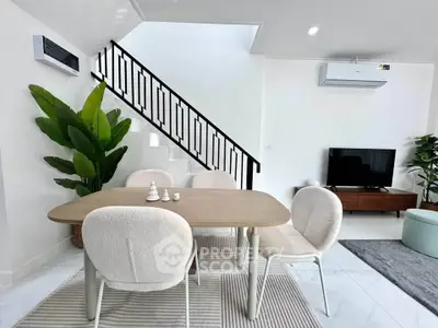 Modern living room with stylish dining area and staircase, featuring contemporary furniture and decor.
