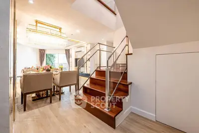 Elegant dining area with chandelier and wooden staircase in modern home