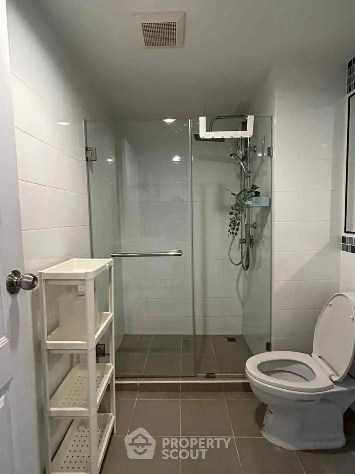 Modern bathroom with glass shower and white shelving unit