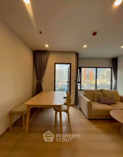 Spacious living room with city view, modern furniture, and large windows in a high-rise apartment.