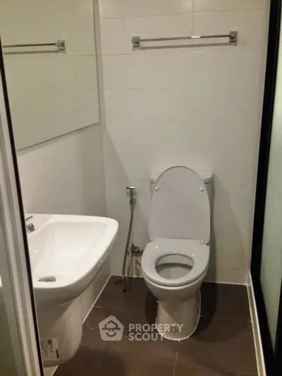 Compact bathroom with modern fixtures and tiled walls, featuring a toilet and sink.