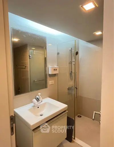 Modern bathroom with glass shower and sleek vanity in contemporary apartment.