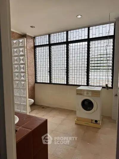 Spacious bathroom with large windows and washing machine, ideal for modern living.