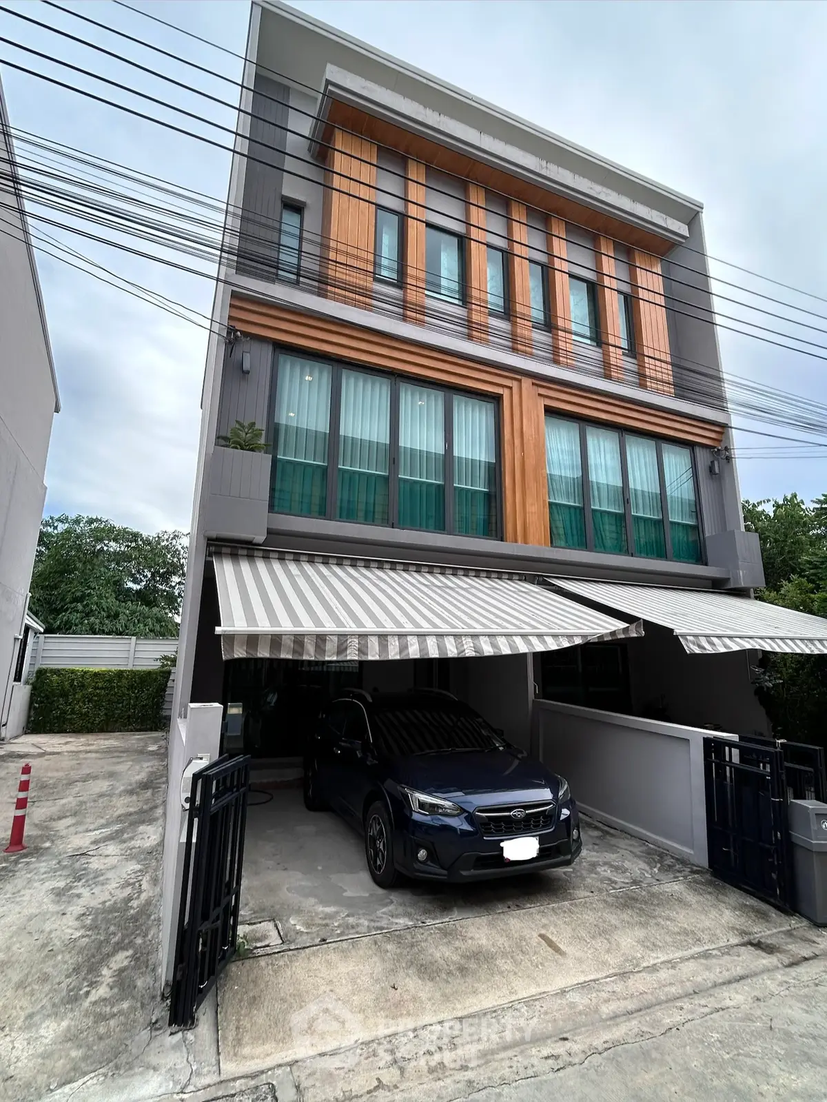 Modern three-story townhouse with carport and stylish facade in urban setting.