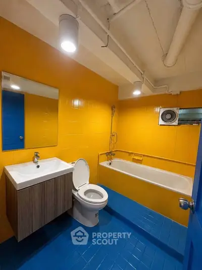 Vibrant yellow and blue bathroom with bathtub and modern fixtures.