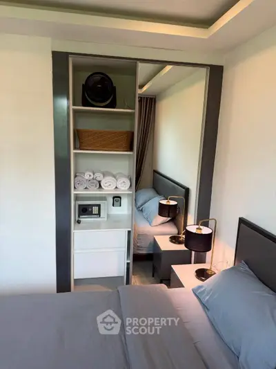 Modern bedroom with sleek design, featuring mirrored wardrobe and stylish bedside lamps.