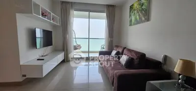 Modern living room with ocean view, featuring a cozy sofa and wall-mounted TV, perfect for relaxation.