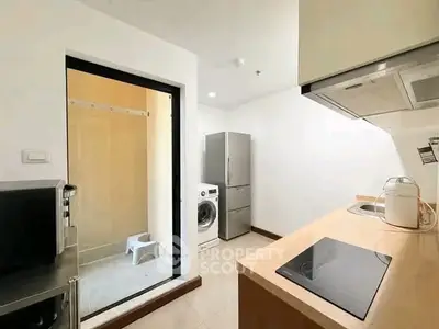 Modern kitchen with sleek appliances and open layout, featuring a washing machine and fridge.