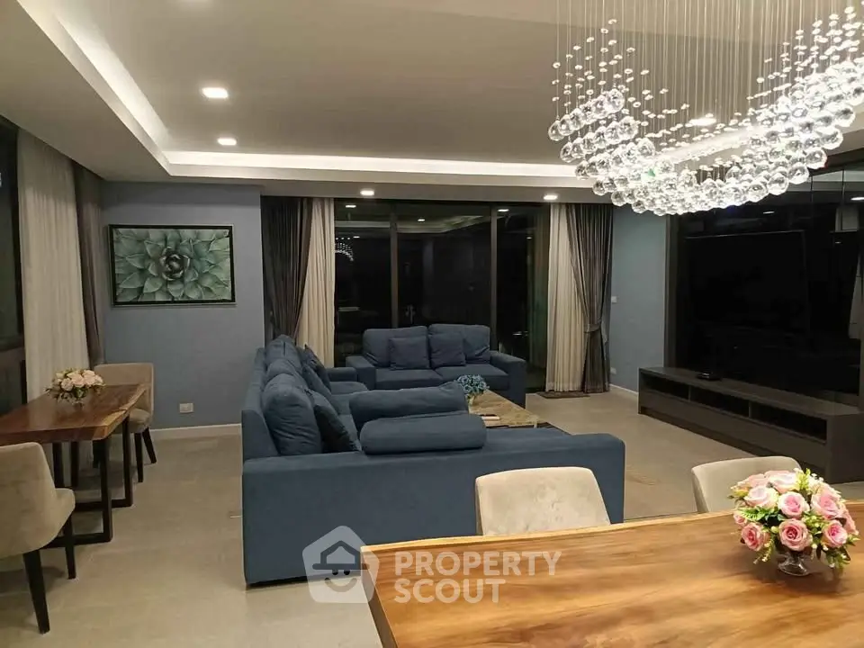 Luxurious modern living room with elegant chandelier and plush blue sofas