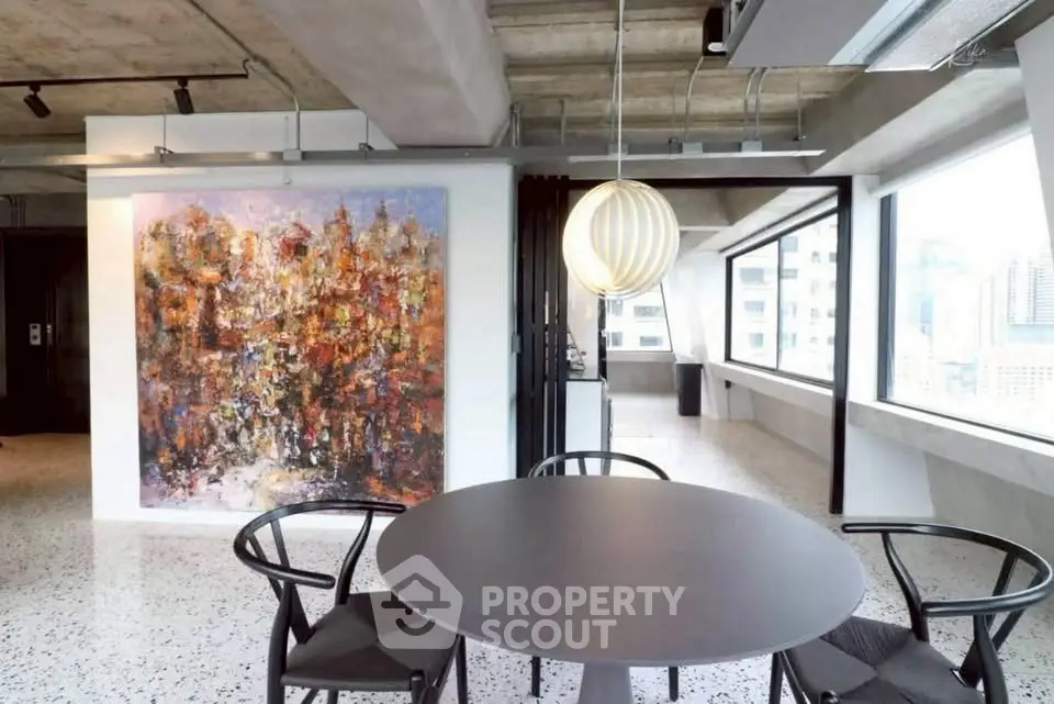 Modern living room with abstract art and city view, featuring stylish round table and chairs.