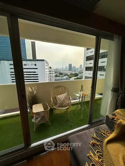 Charming balcony with city view, cozy seating, and lush artificial grass, perfect for relaxation.