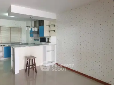 Modern kitchen with open layout and stylish decor, featuring a breakfast bar and contemporary lighting.