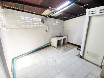 Spacious utility room with tiled floor and sink, ideal for laundry or storage.